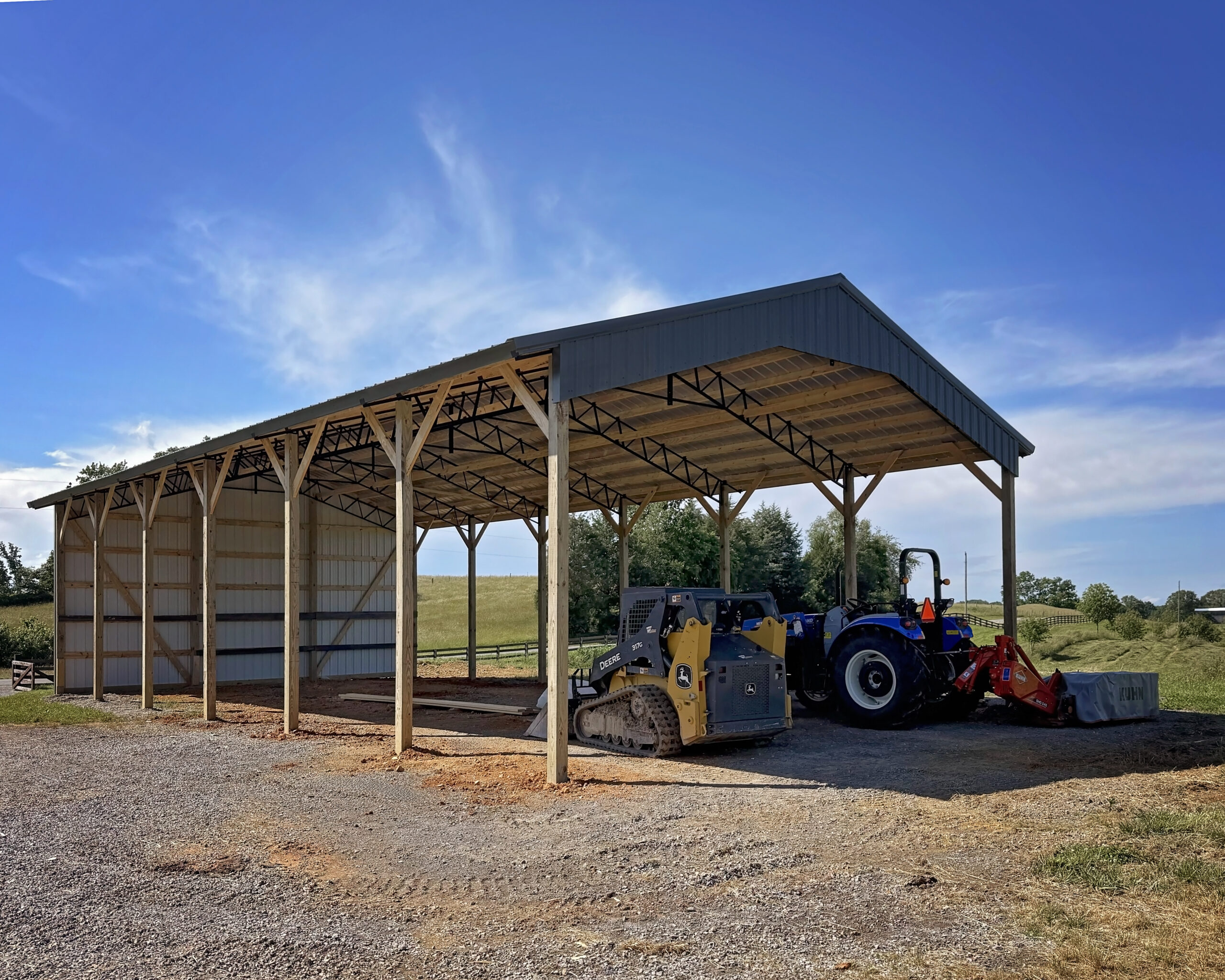 Black-roofed agricultural pole barn with farm equipment