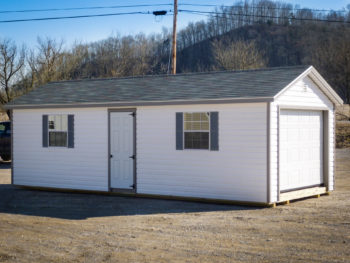 A garage shed in Kentucky with white vinyl siding and two windows with shutters