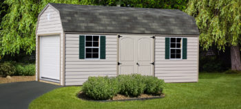 A barn-style storage building in Kentucky with vinyl siding and two windows with shutters