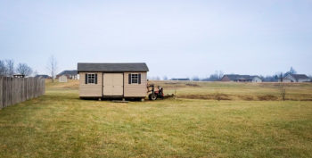 A shed being delivered in Kentucky with vinyl siding and a shingle roof