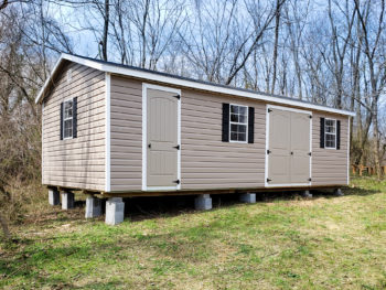 A vinyl shed in Kentucky with double doors, windows, and black shutters