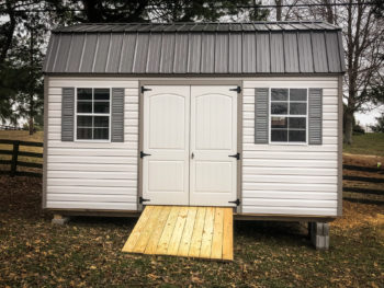 A lofted vinyl shed in Kentucky with double doors, windows, and shutters