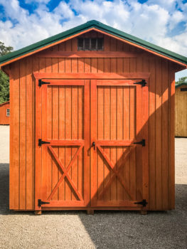 A shed in Tennessee with wooden siding and a green metal roof