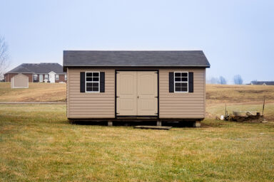 A garden shed in Tennessee with vinyl siding, double doors, windows, and a shingle roof