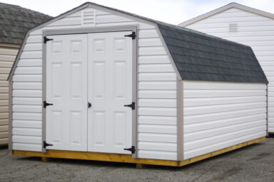 A portable shed in Kentucky with white vinyl siding, a shingle roof, and double doors