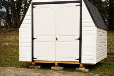 A portable shed in Tennessee with vinyl siding, a black shingle roof, and double doors