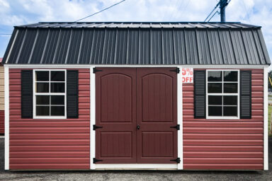 A discounted outdoor shed in Tennessee with red vinyl siding, double doors, and a metal roof