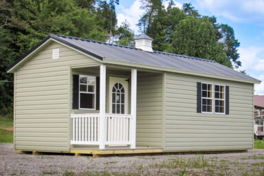 A prefab cabin in Tennessee with vinyl siding, a corner porch, and a cupola