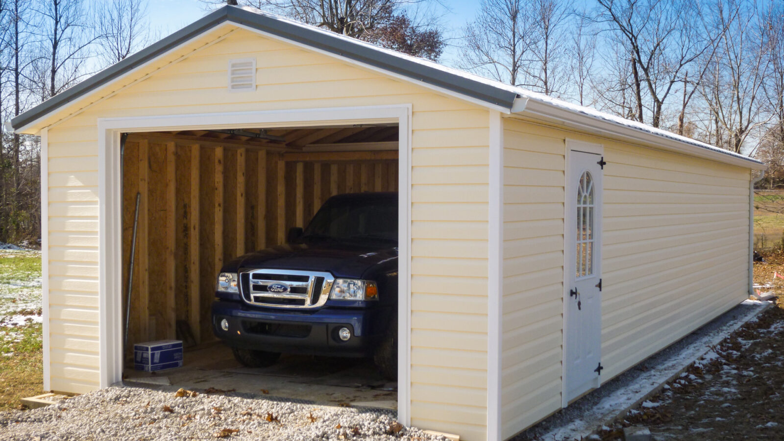 exterior of yellow garage shed with car